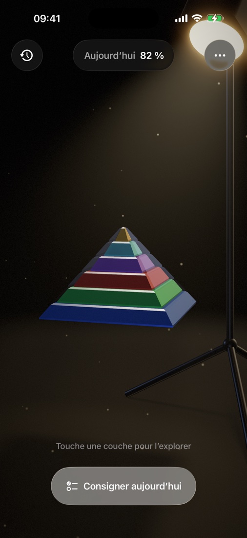 La pyramide Maslow — six couches colorées sous la lumière chaude d'un projecteur de studio