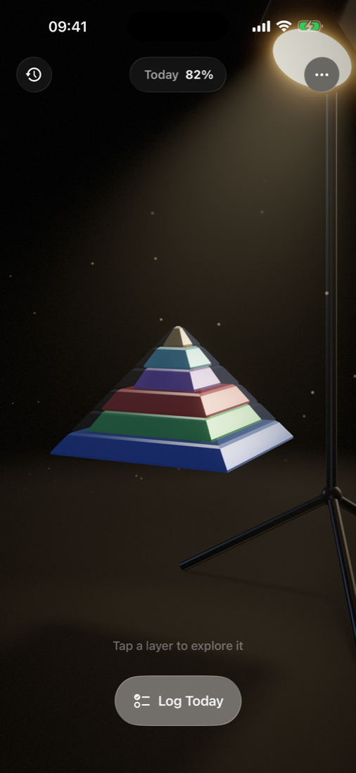 The Maslow pyramid — six colored layers lit by a warm studio projector