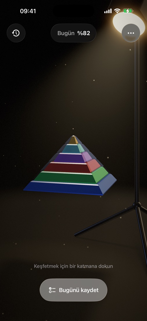 Maslow piramidi — stüdyo projektörünün sıcak ışığında altı renkli katman